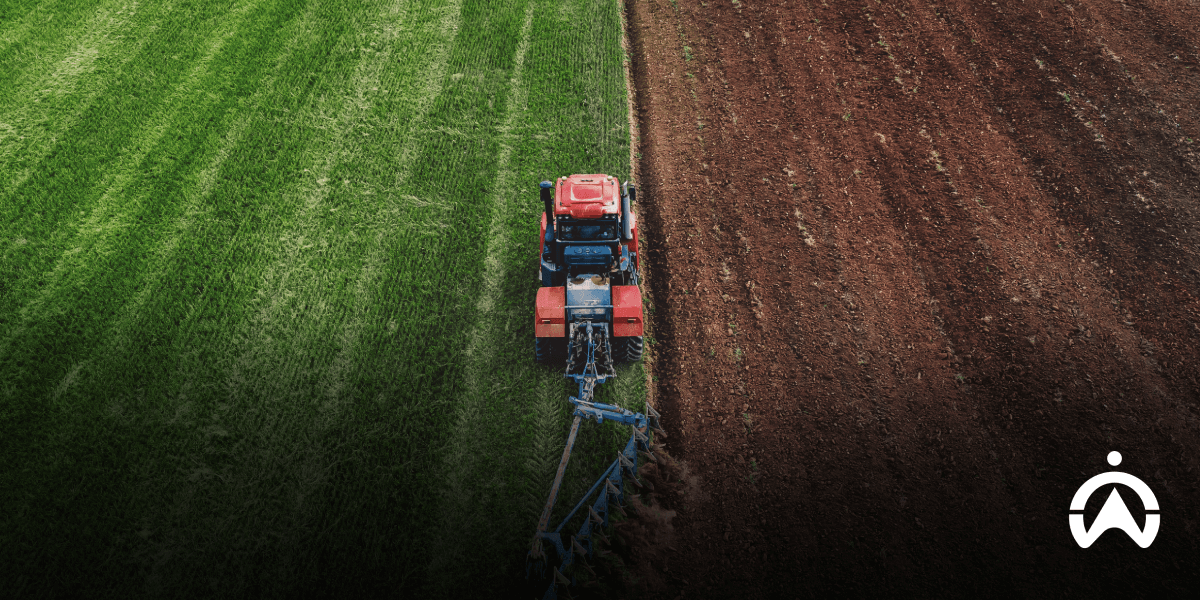 Cartrack agriculture fleet management software view of a tractor ploughing between green grass and brown soil.