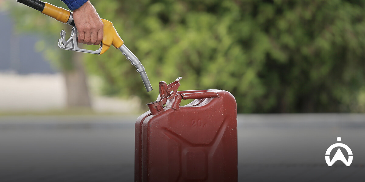 Hand holding a yellow fuel pump nozzle above a red canister demonstrating fuel efficiency management.