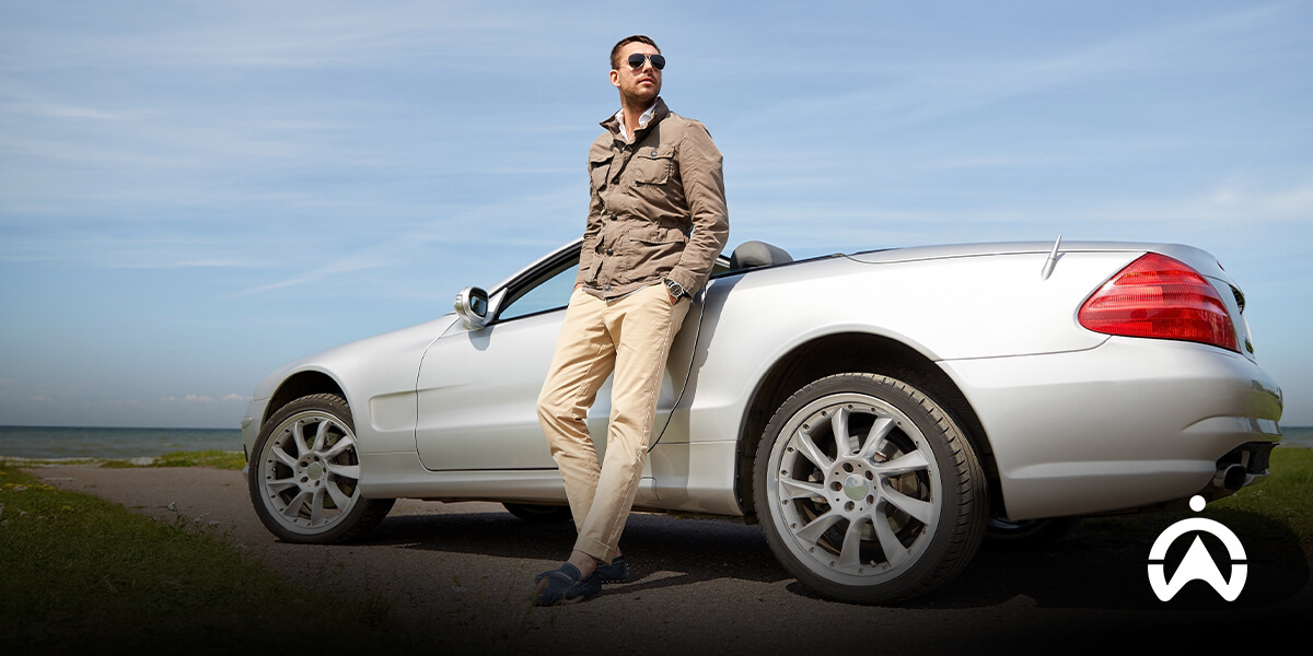 Man standing by silver convertible showcasing personal car tracking device benefits.