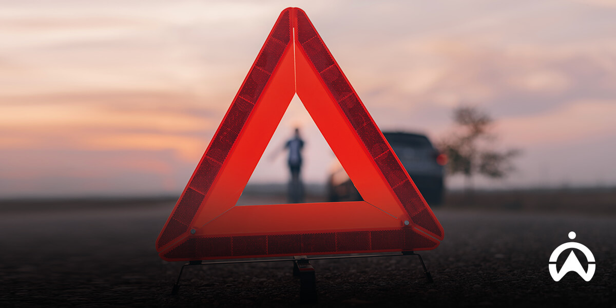 Warning triangle on road after car accident at dusk.