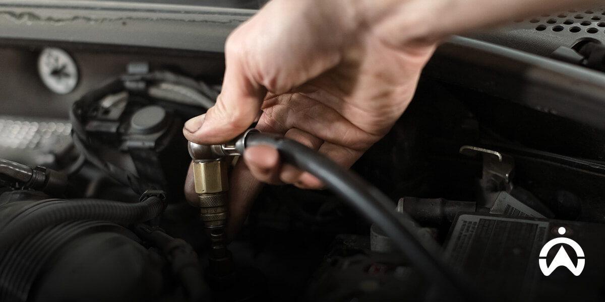 Hand connecting hose for engine maintenance, showing car checks you should never skip before a long road trip.