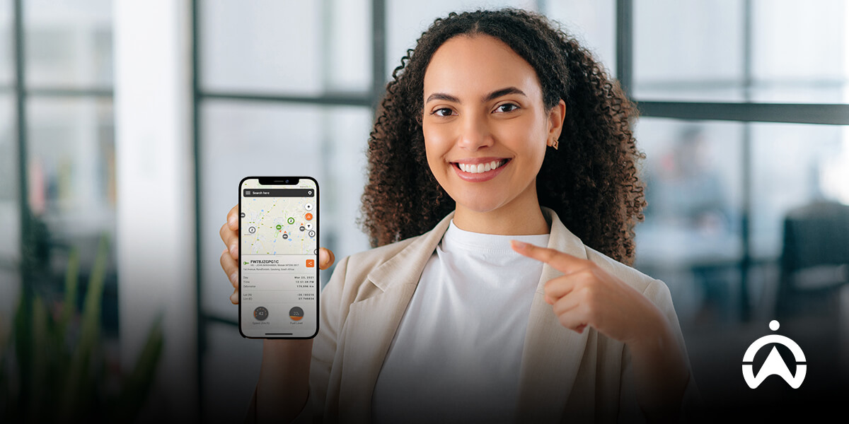 Woman holding a smartphone showing Cartrack app with map and vehicle location data for national vehicle tracking.