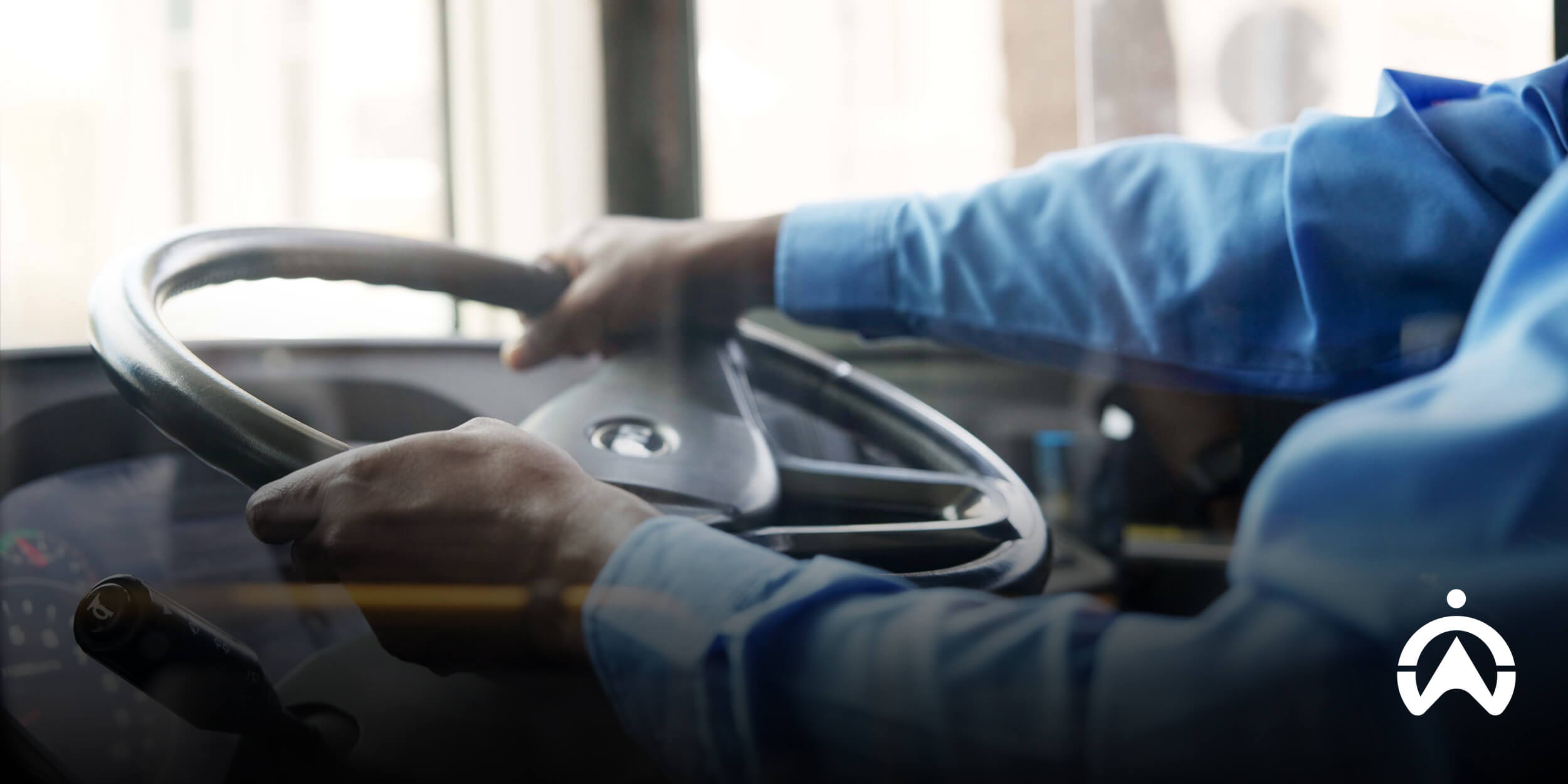 A school lift transport driver in a blue t-shirt holding a bus steering.