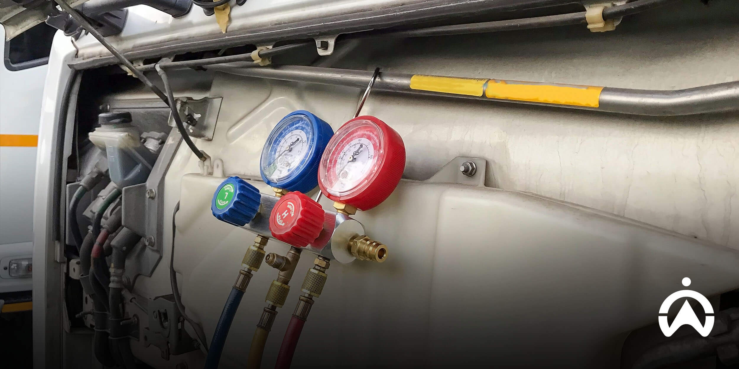 Technician using HVAC pressure gauges on refrigerated vehicle, supporting Cartrack cold chain temperature monitoring.