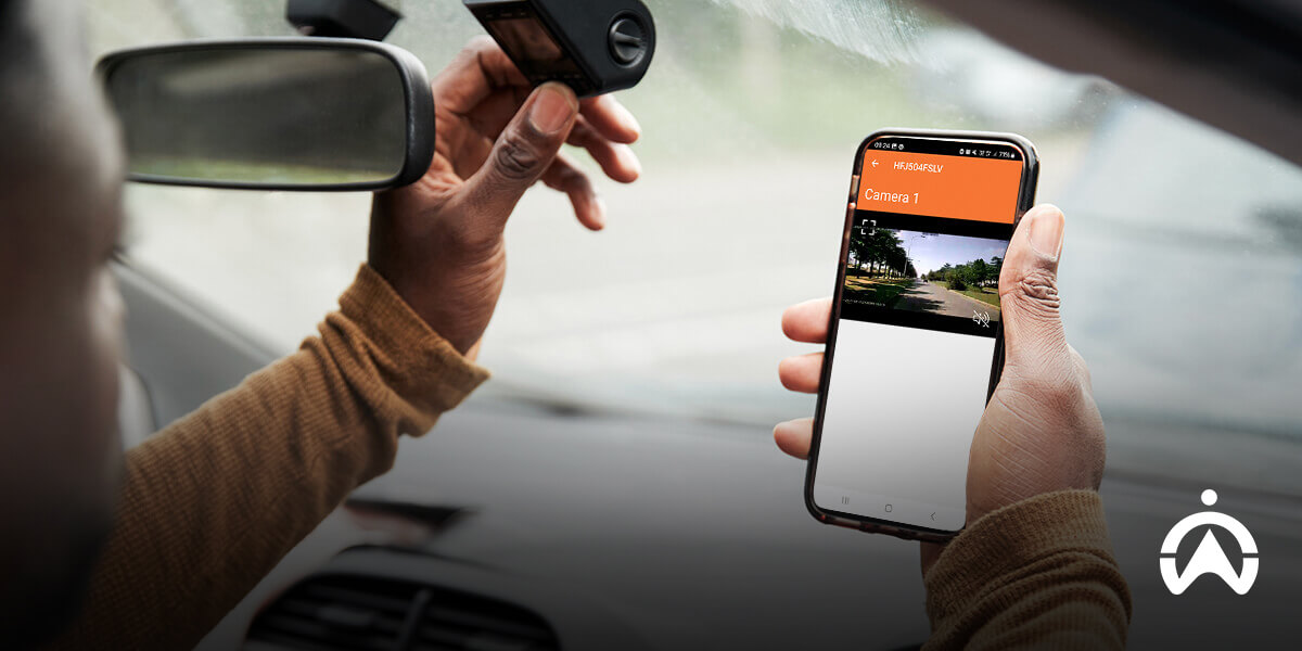 Person inside a car holding Cartrack dashcam and viewing its live footage on a Cartrack mobile app.