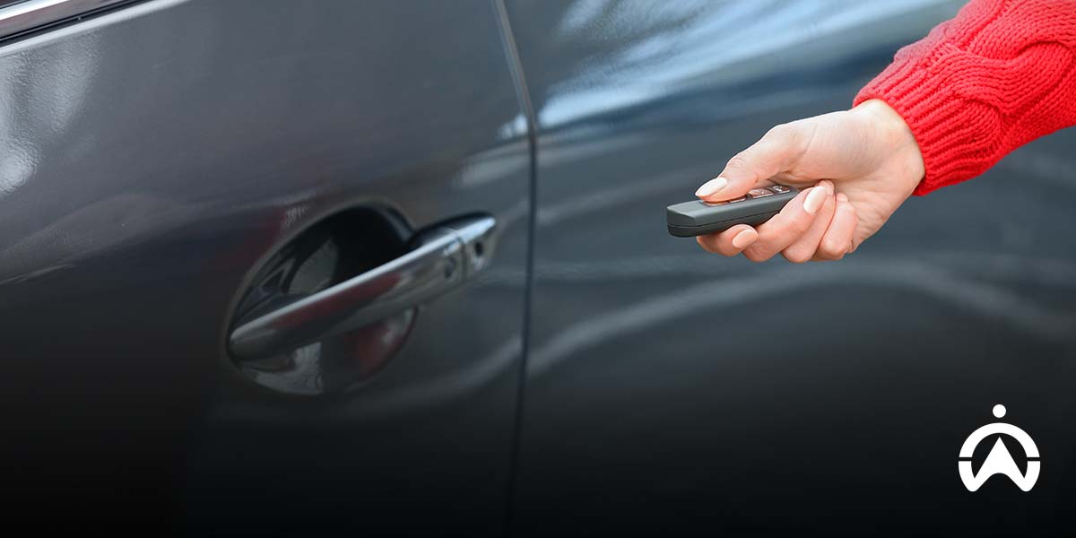 Person unlocking car with remote key, illustrating remote jamming risks and vehicle access security.