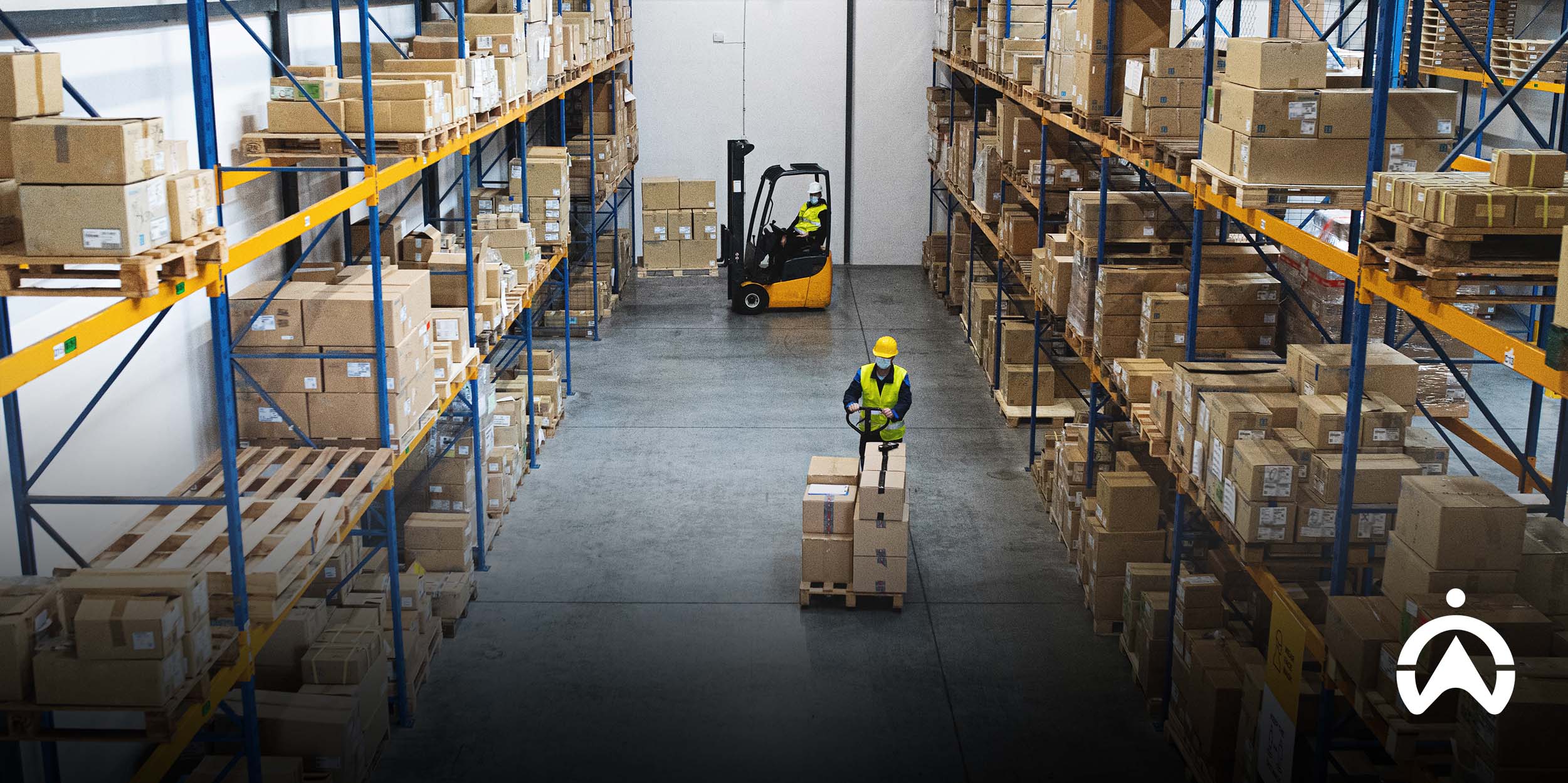 Warehouse workers wearing safety gear organize pallets and stocked racks, showcasing efficient operations managed by forklift fleet management software.