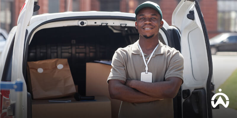 Delivery driver standing confidently by a loaded van, representing high driver retention and reduced recruitment costs for logistics businesses.