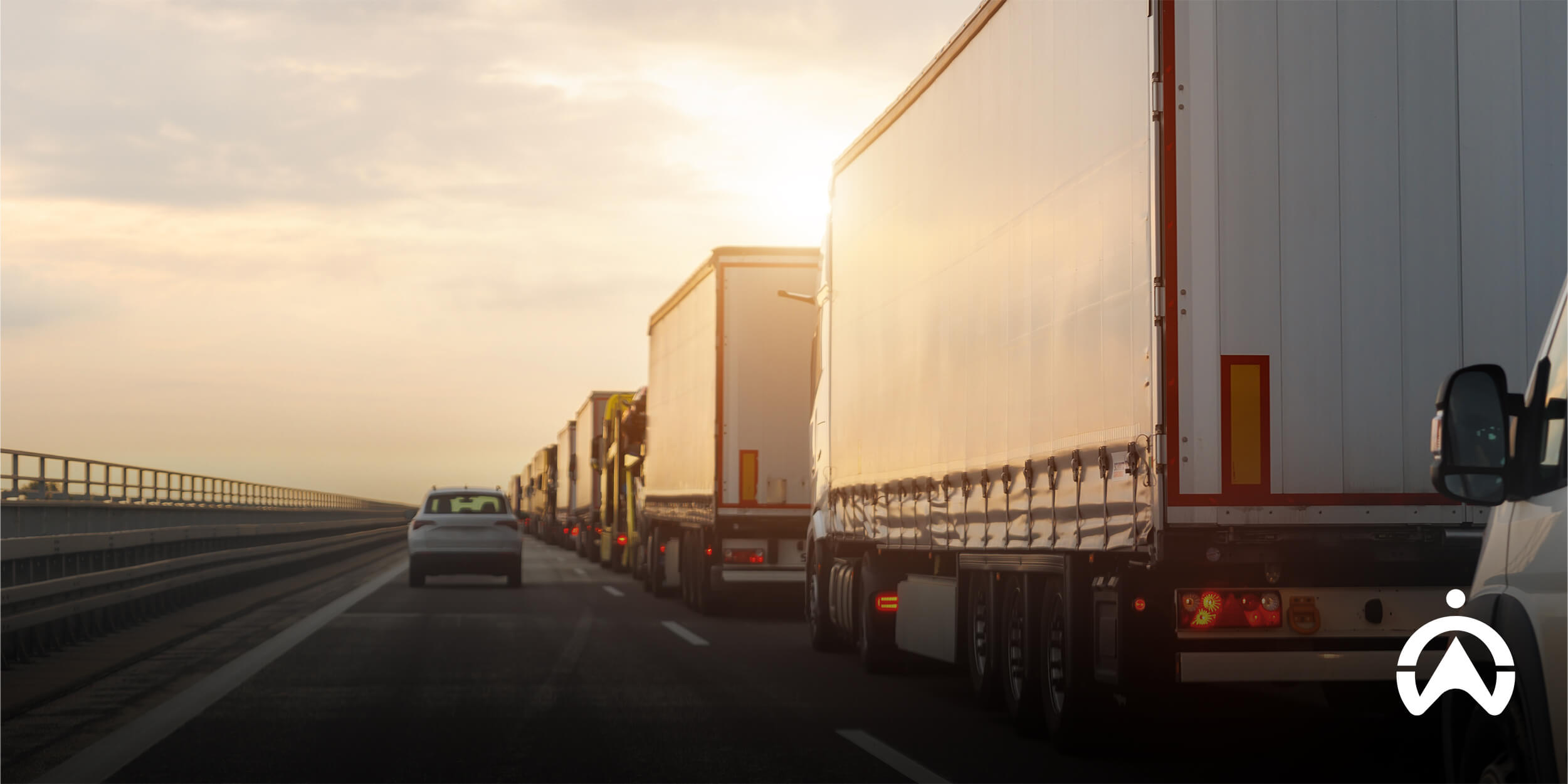 Semi-trucks lined up on a highway at sunset, representing how to successfully manage cross-border logistics and long-distance freight movement