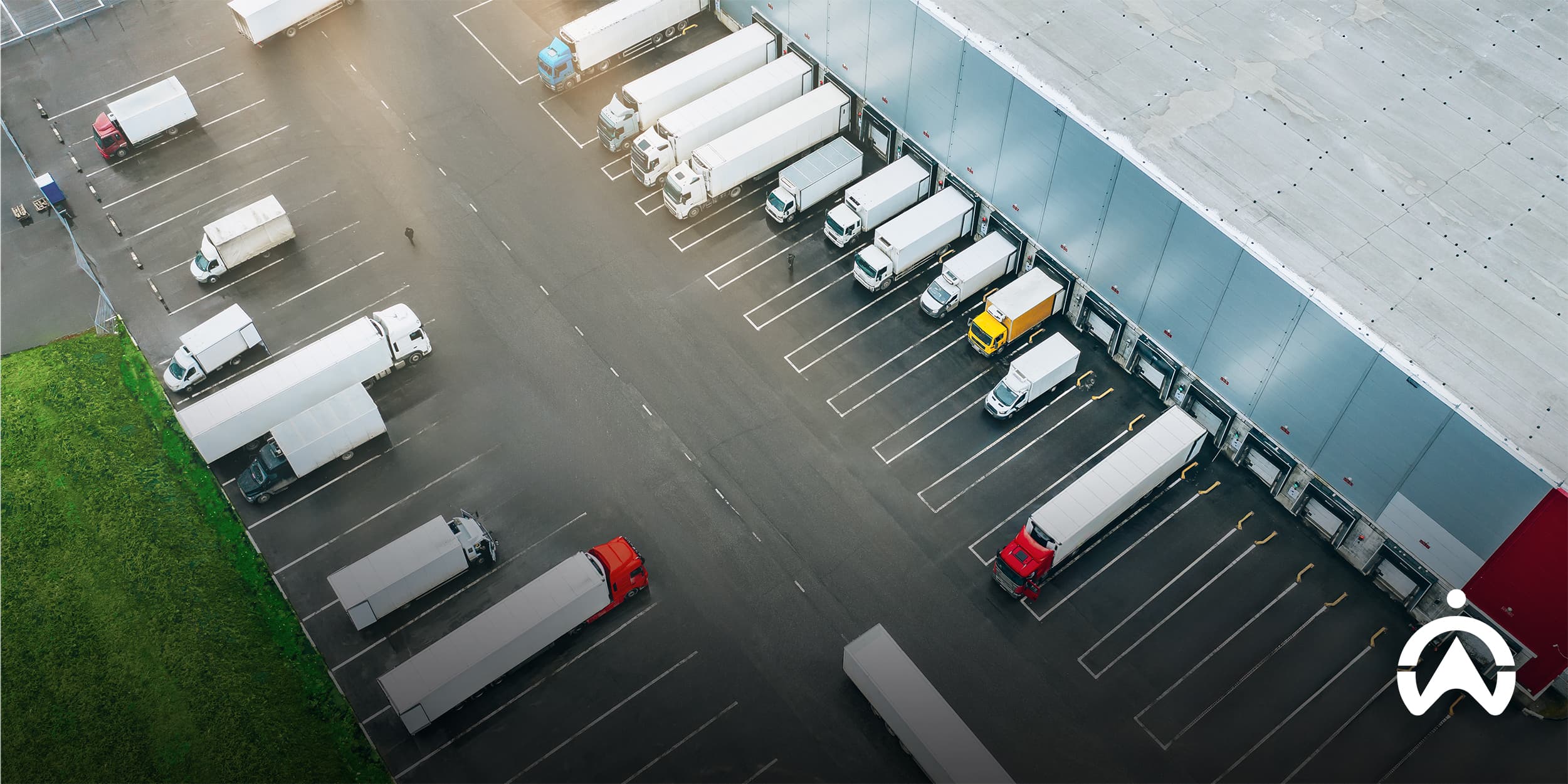 Aerial view of warehouse with trucks at loading docks, showing how to successfully manage cross-border logistics and distribution operations