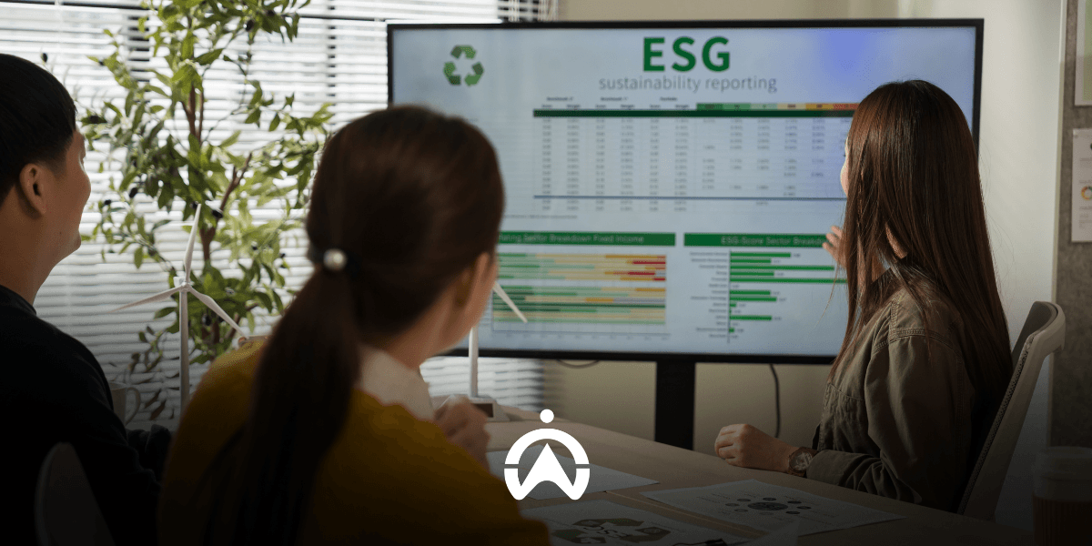 Three colleagues discussing ESG sustainability reporting and carbon footprint data in fleet management displayed on a meeting room screen.