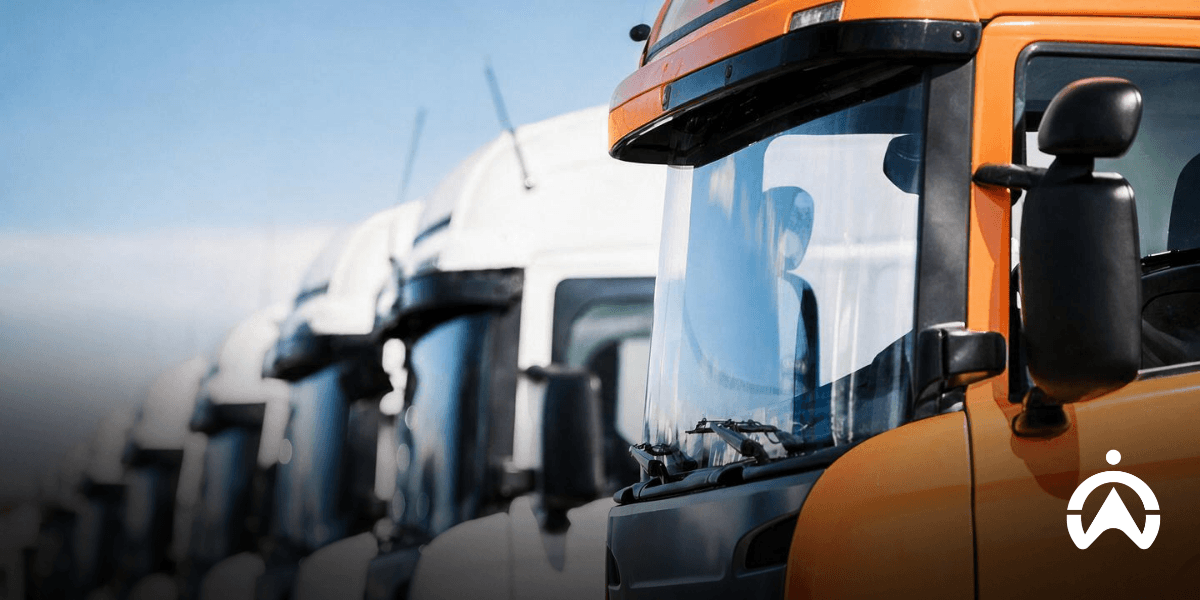 A row of trucks lined up with a orange truck in the front