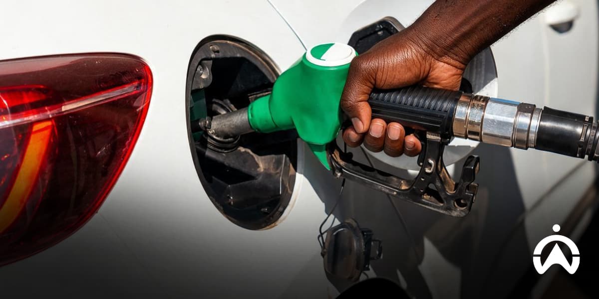 Hand refuelling a white car with a green petrol nozzle, illustrating fuel choices when comparing petrol types in South Africa.
