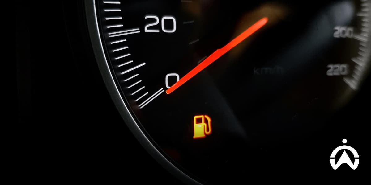 Close-up of a car speedometer with a low-fuel warning light, highlighting fuel efficiency when choosing the best petrol in South Africa.