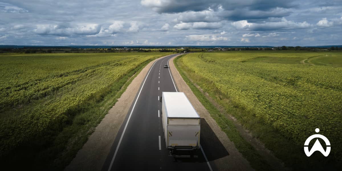 NGO fleet management truck driving on a rural highway through remote green fields.