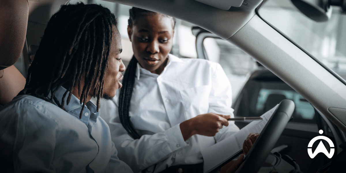 Two professionals reviewing vehicle paperwork inside a car, discussing car safety and import requirements for moving to South Africa.