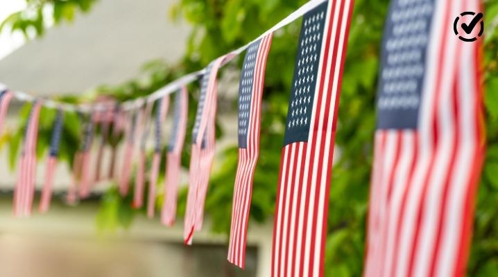 American flag bunting hanging outdoors with greenery in the background.
