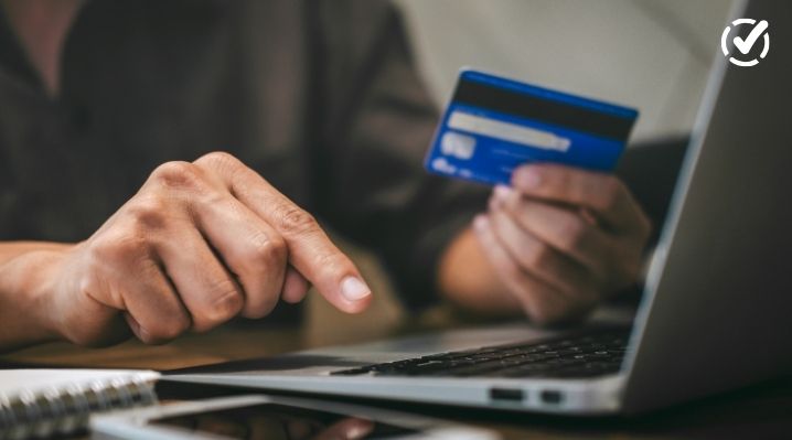 A close-up, high-angle shot of a person's hands using a laptop while holding a blue credit card, representing online banking or financial management. A white Formative logo is visible in the top right corner.