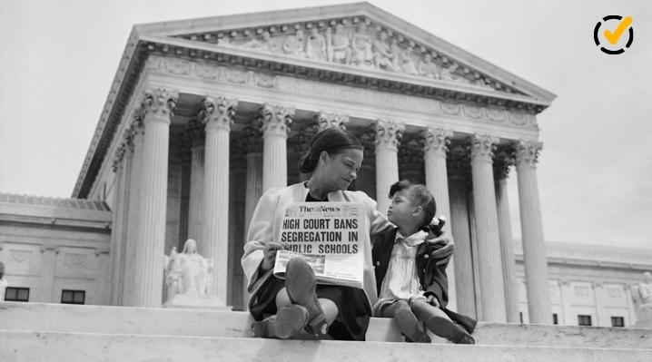 "A black and white photo of an adult woman holding a newspaper with the headline 'High Court Bans Segregation in Public Schools' while a child sits next to her, both looking at each other on the steps of the Supreme Court building. The Formative by Newsela