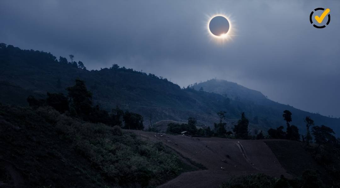A high-contrast photograph of a total solar eclipse over a dark, mountainous landscape under a cloudy sky. The Formative by Newsela icon is in the top right corner.