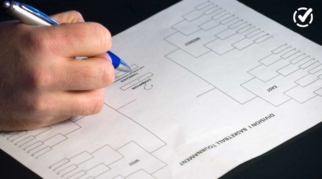 Close-up of a person's hand using a blue pen to fill out a blank NCAA Division I Basketball Tournament bracket. A Formative logo is visible in the top right corner.