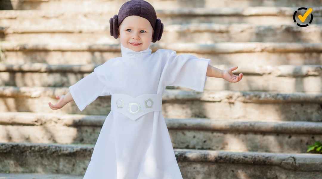 A young child dressed in a Princess Leia costume with iconic hair buns and a white robe, smiling with arms outstretched on stone steps. Includes the Formative checkmark logo in the corner.