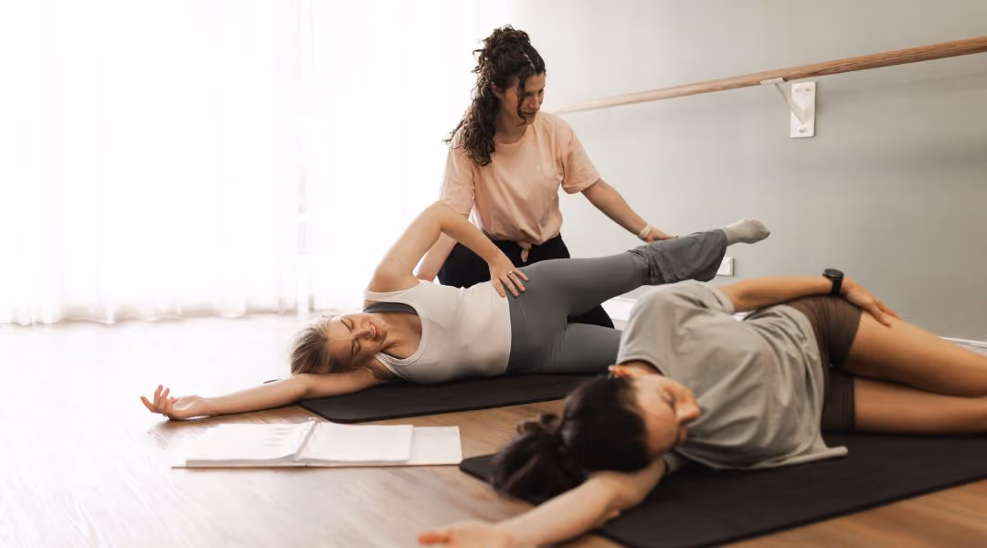 mat pilates instructor adjust student