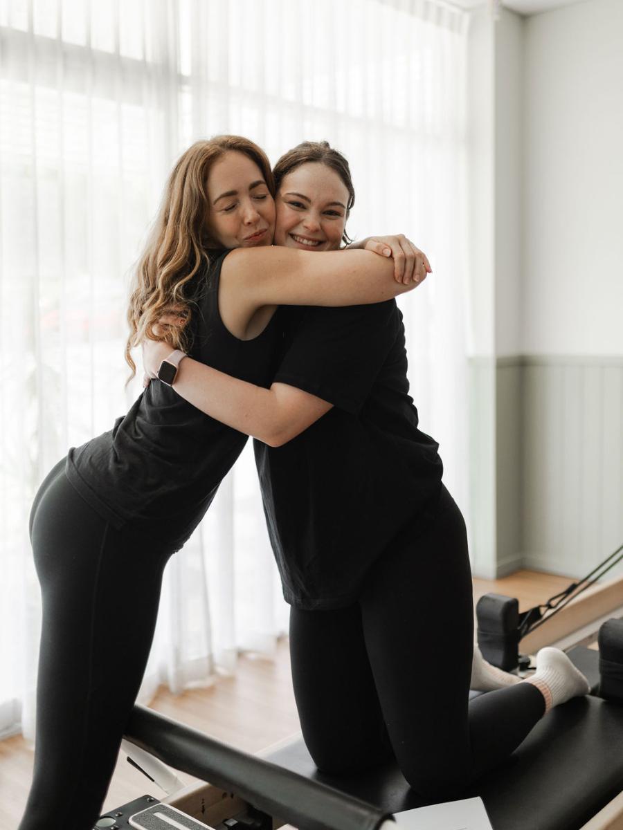 A Pilates instructor and client sharing a warm hug in the studio after class at Premium Pilates and Fitness