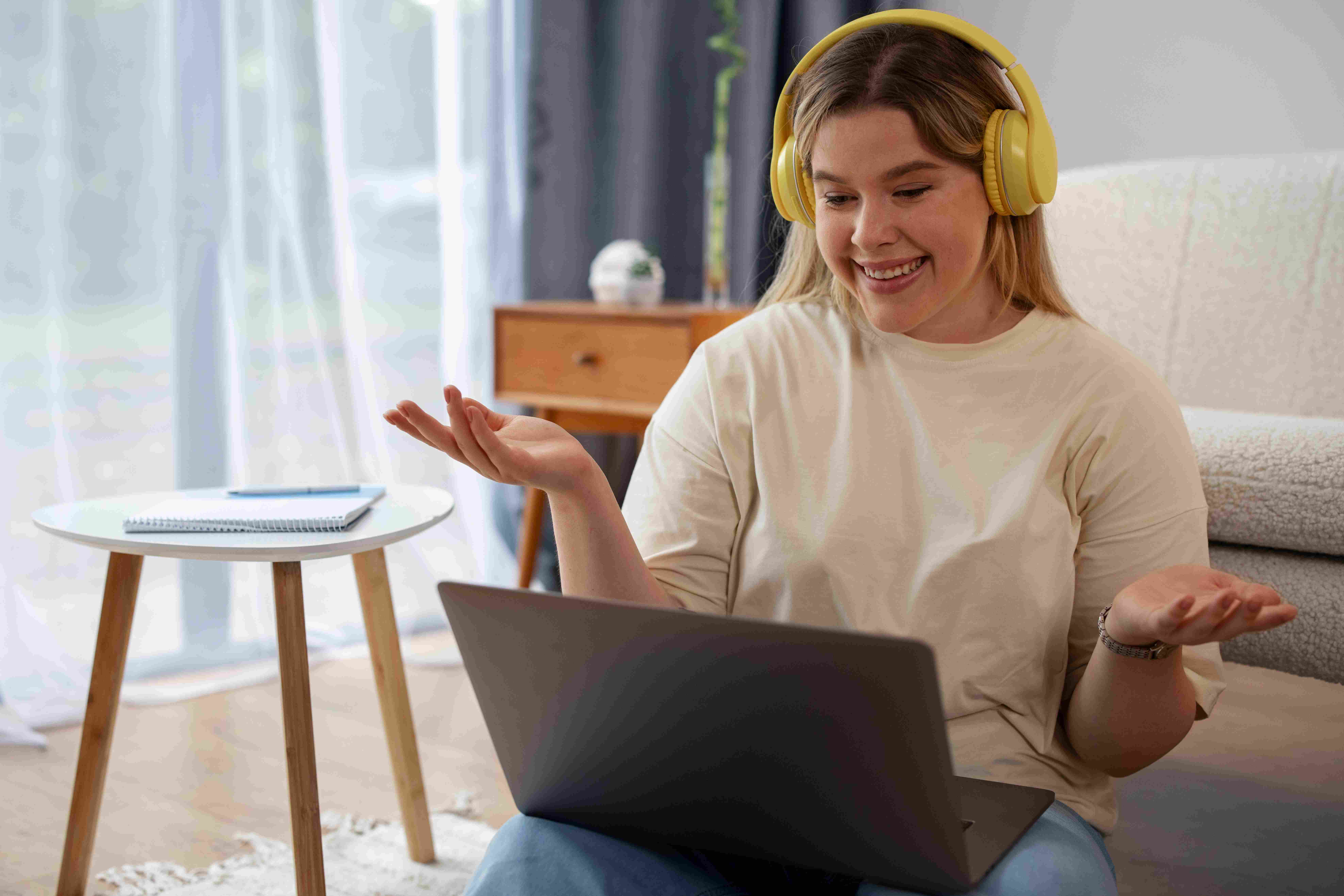 Mulher de fones de ouvido, sorrindo e olhando para o notebook durante sessão de terapia.