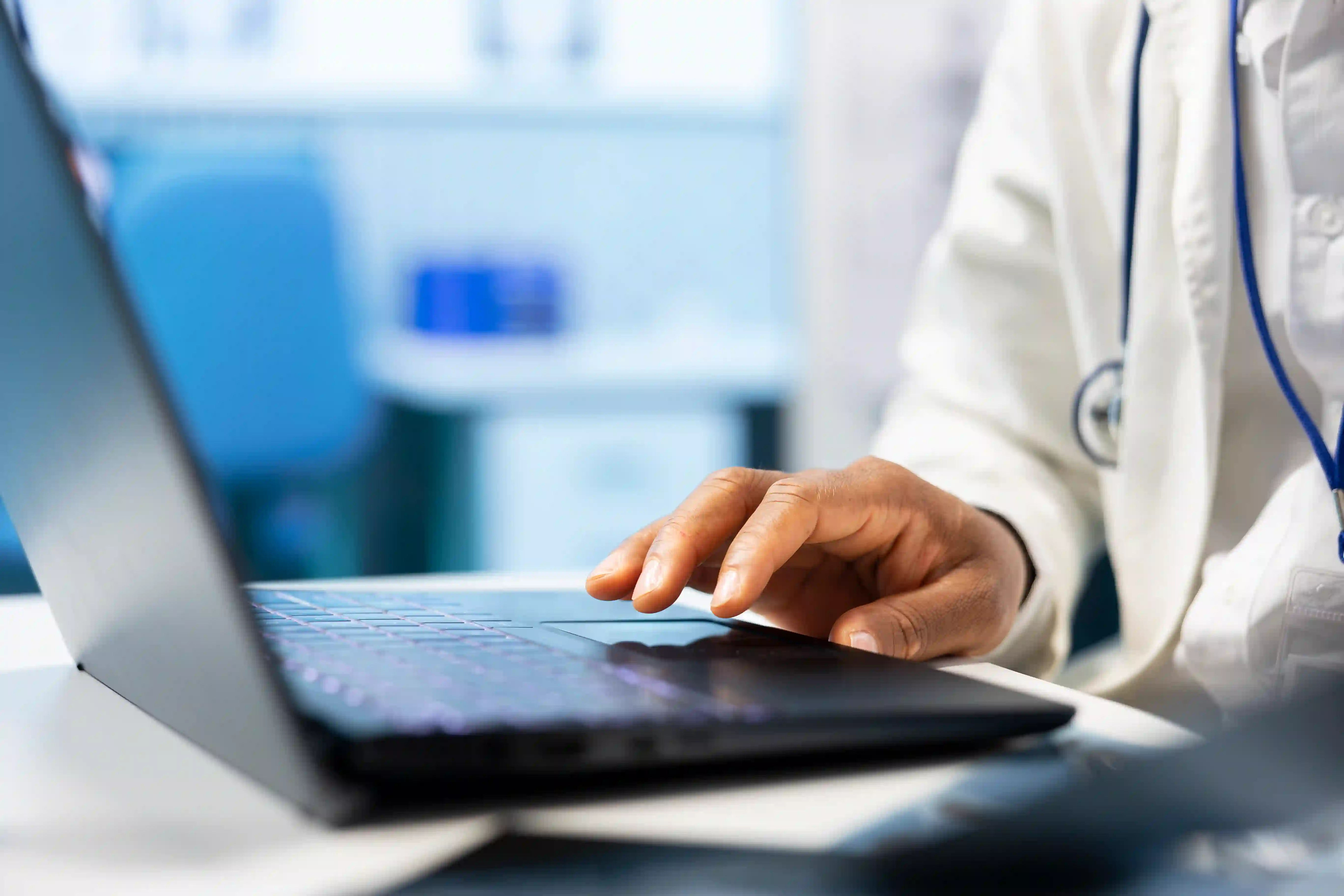 Médico mexendo no mouse do notebook com uma mão.