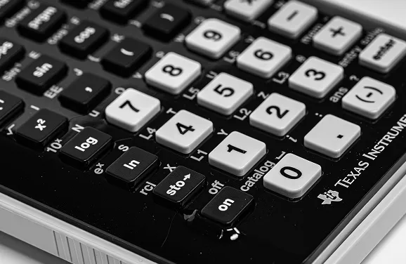 Close-up of a black and white calculator showing function and number keys.