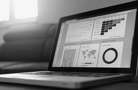 Laptop displaying data analytics dashboard with charts, graphs, and a world map on screen.