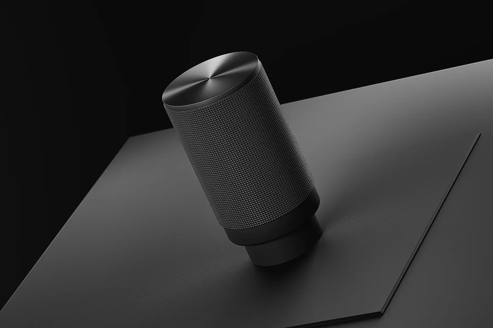 Svart metallrund ratt med texturerad yta på en svart platt yta.