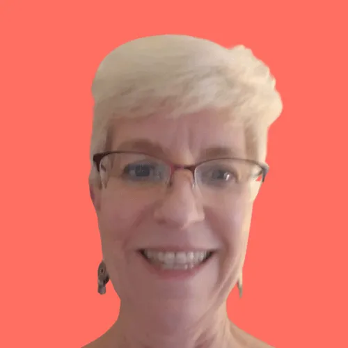 Smiling woman with short white hair, wearing glasses and dangling earrings, against a solid coral background.
