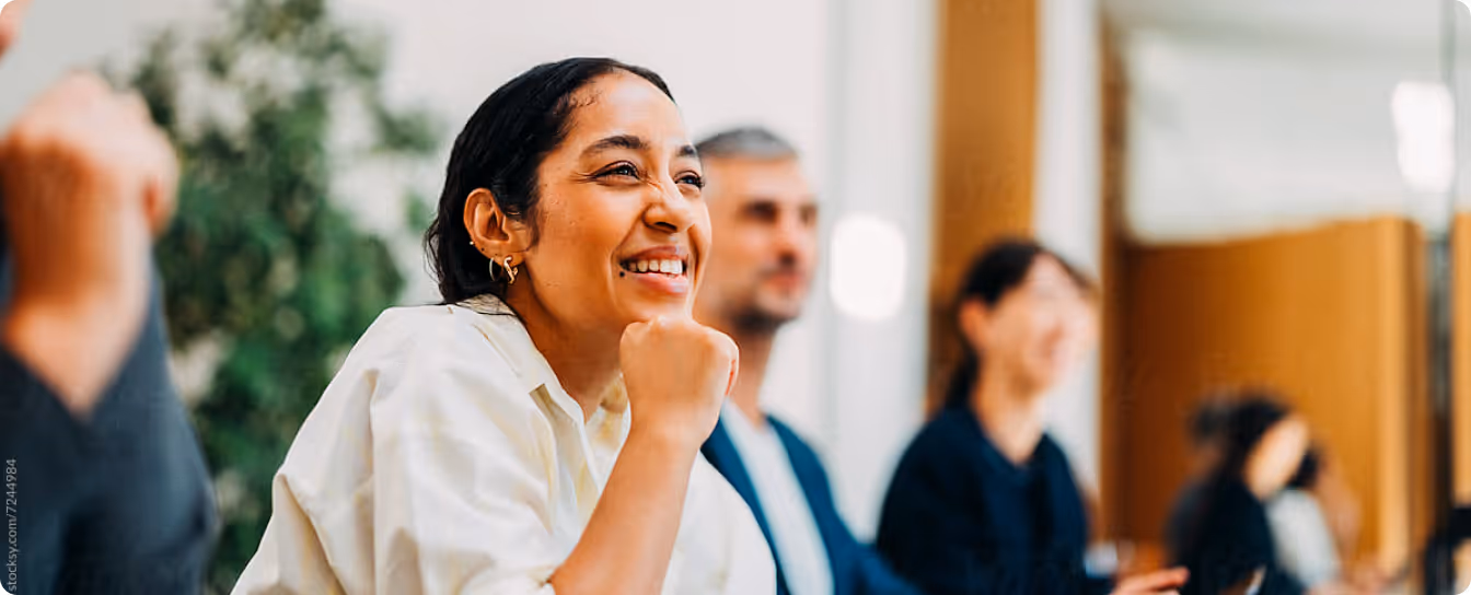 Smiling woman with hand on chin sitting in a group discussion indoors.