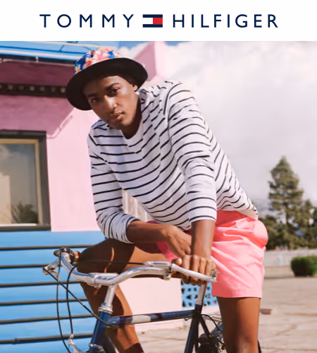 model sitting on a bicycle with pink shorts, plaid bucket had and striped long sleeve. 