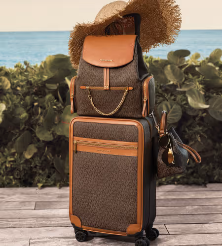 Michael Kors luggage with a sun hat on top