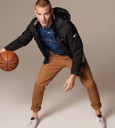 Young man wearing Tommy Hilfiger apparel dribbling a baskeetball
