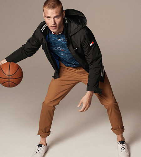 Young man wearing Tommy Hilfiger apparel dribbling a baskeetball