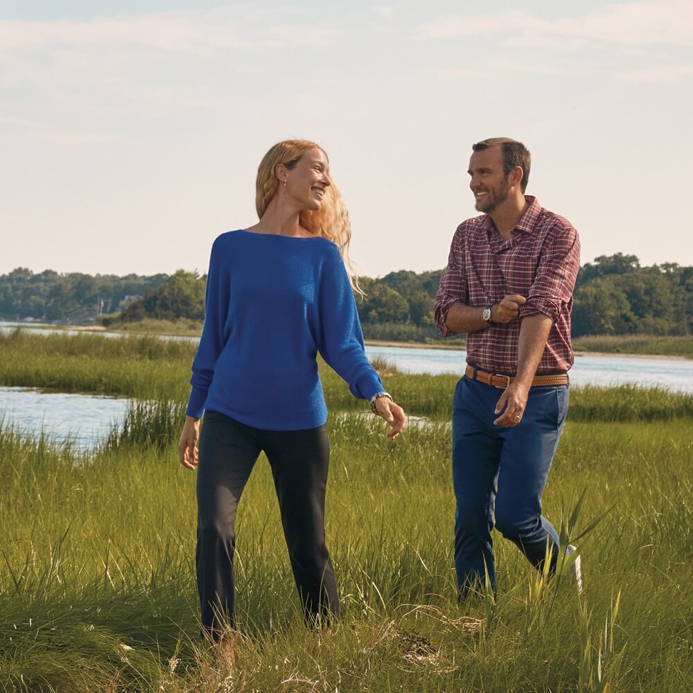 Young couple wearing Tommy Bahama apparel while walking alongside a river