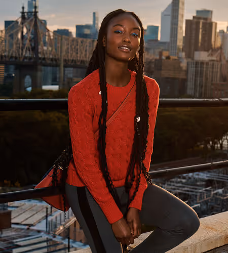 Model on a rooftop wearing red long-sleeve shirt and jeans from Tommy Hilfiger