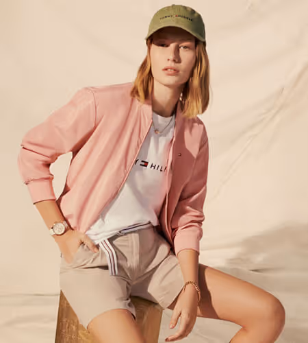 Model wearing Tommy Hilfiger pink button-up shirt, baseball cap, and shorts