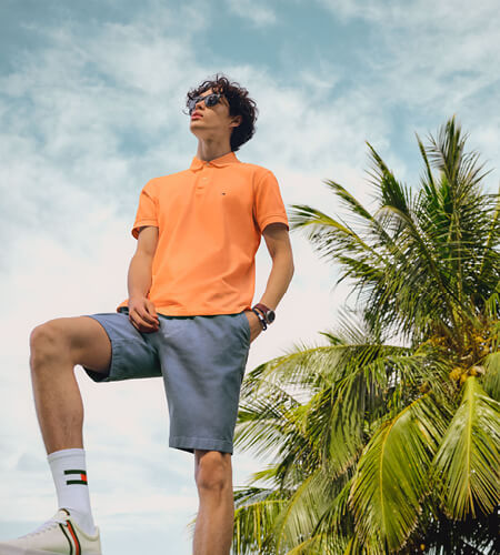 Young man wearing Tommy Hilfiger orange polo shirt and blue shorts