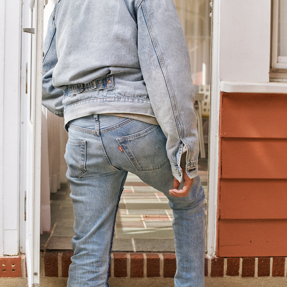 Person wearing denim jeans and jacket walking up stairs