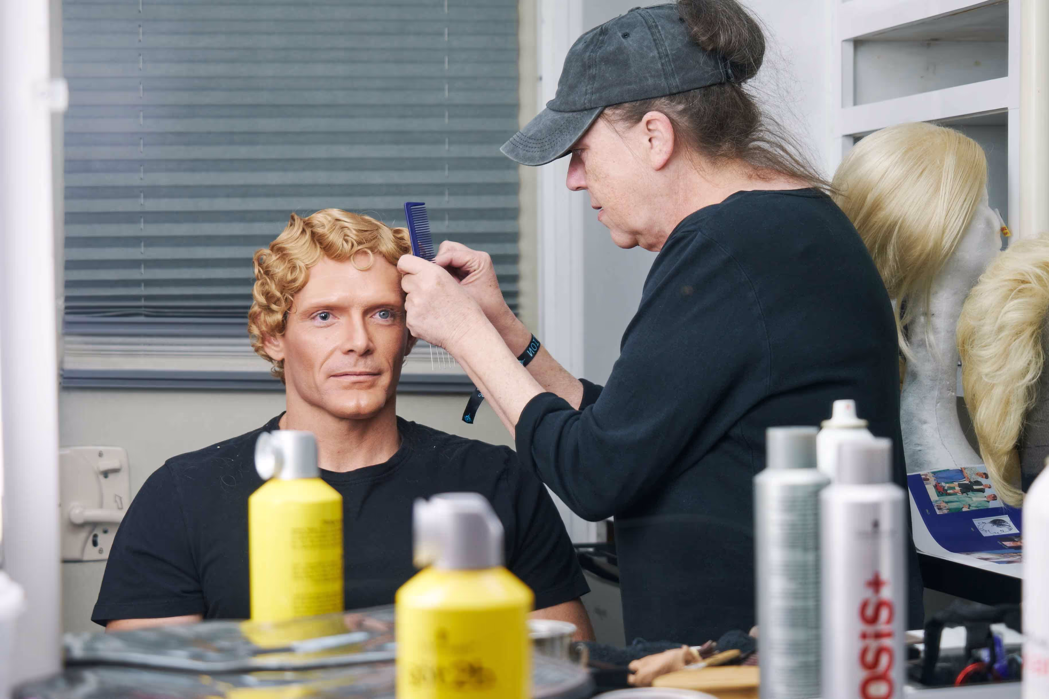 A man getting his hair cut by a mannequin.