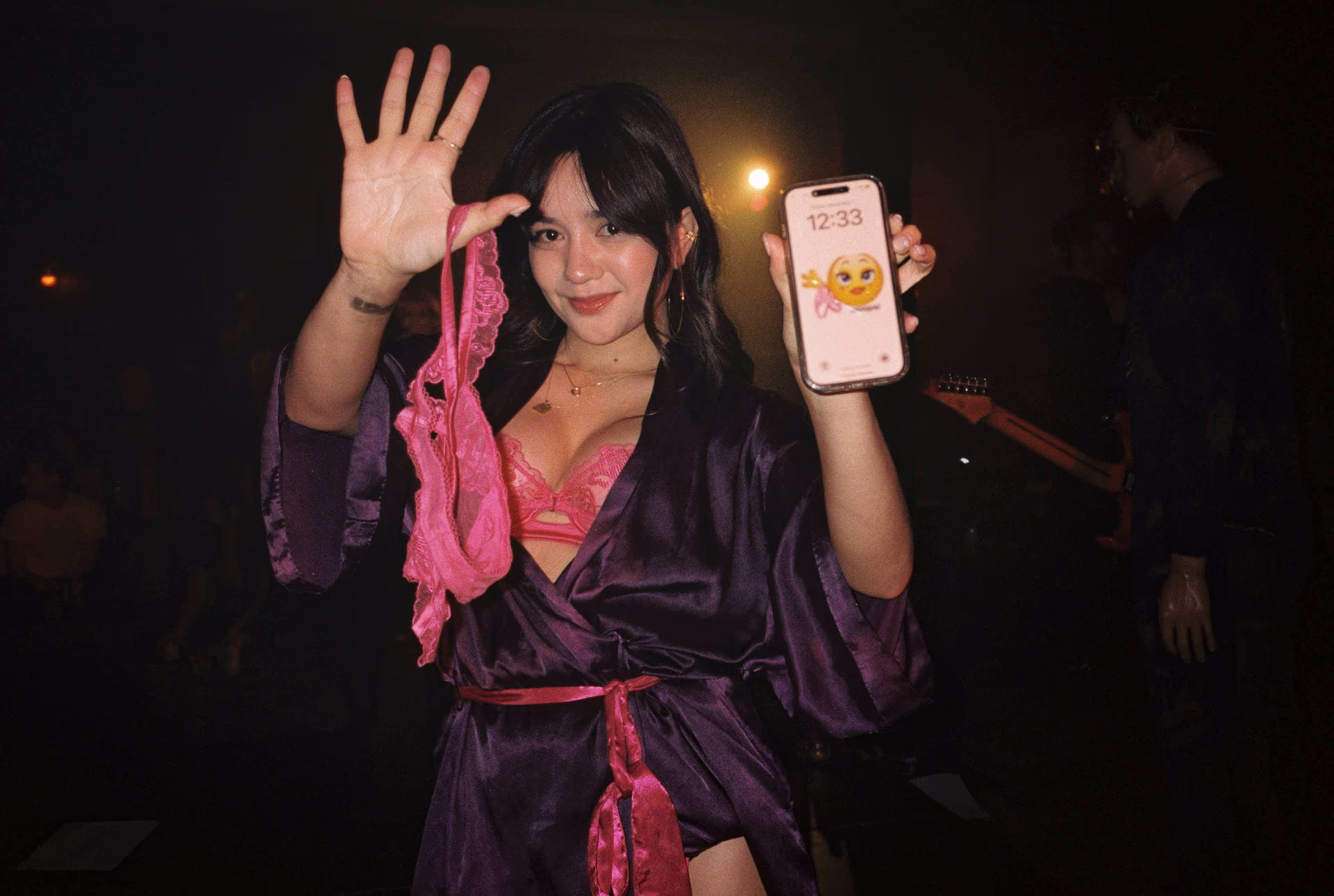 A woman in a robe holding up a cell phone.