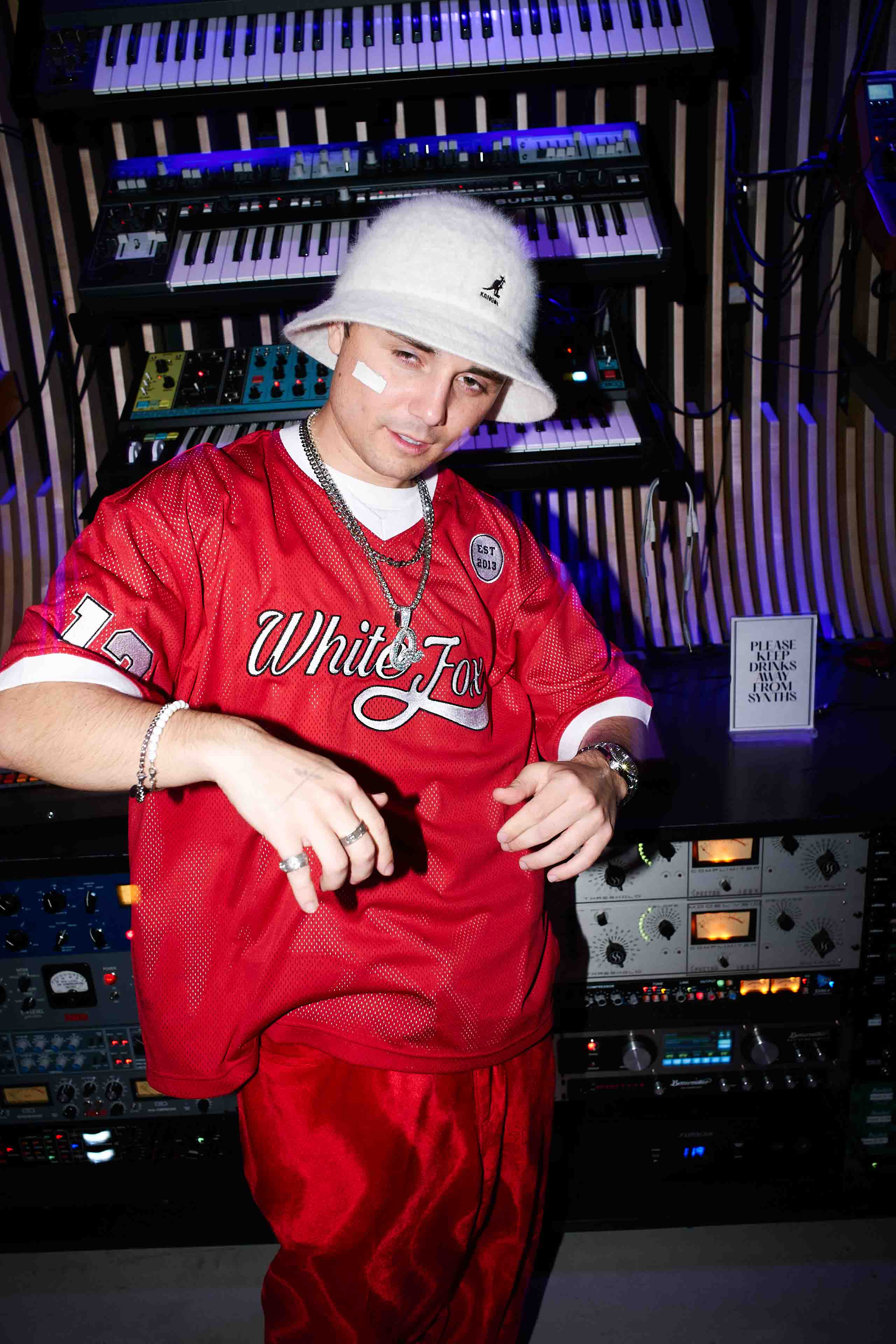 A man in a red shirt and hat standing in front of a keyboard.
