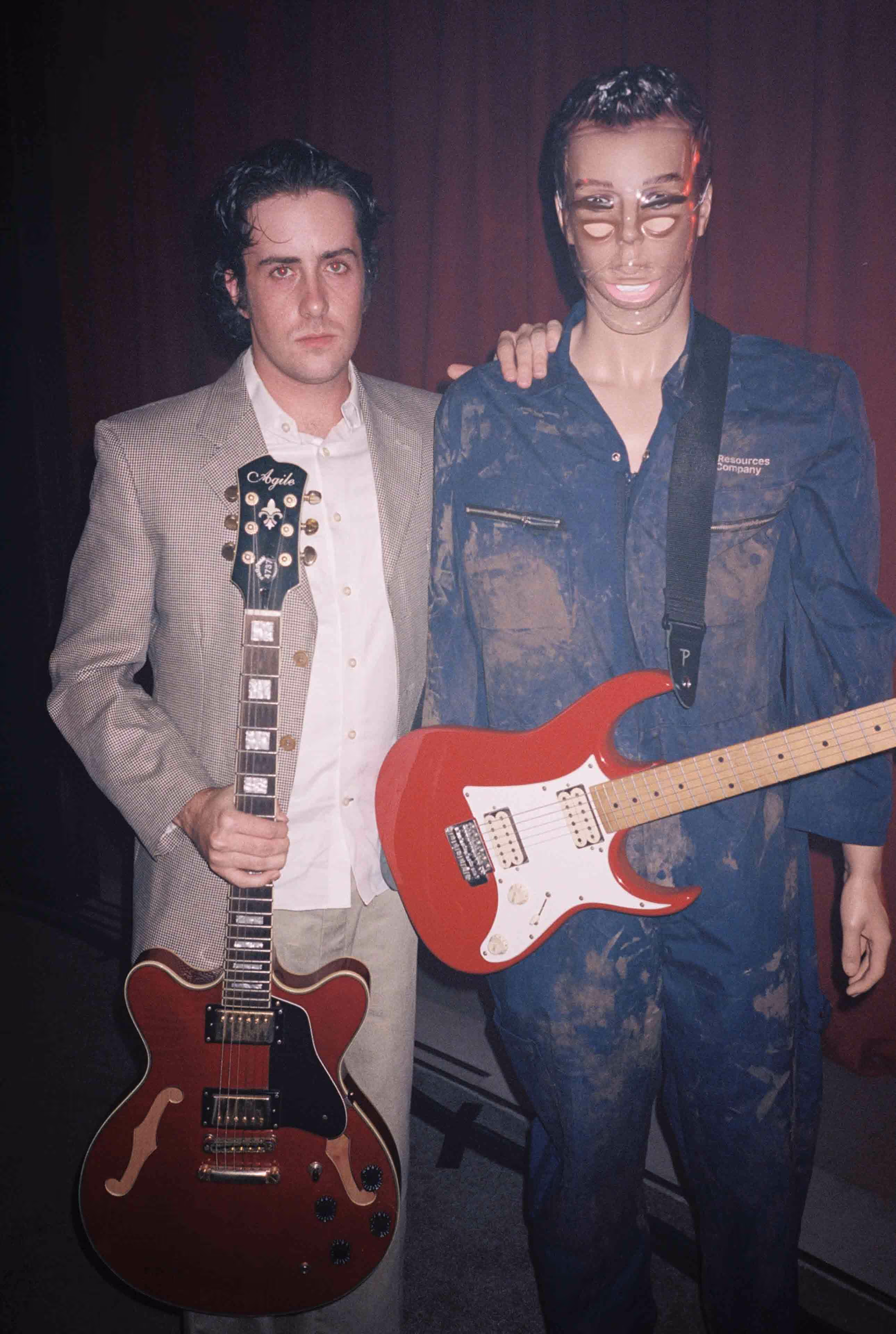 A couple of men standing next to each other holding guitars.