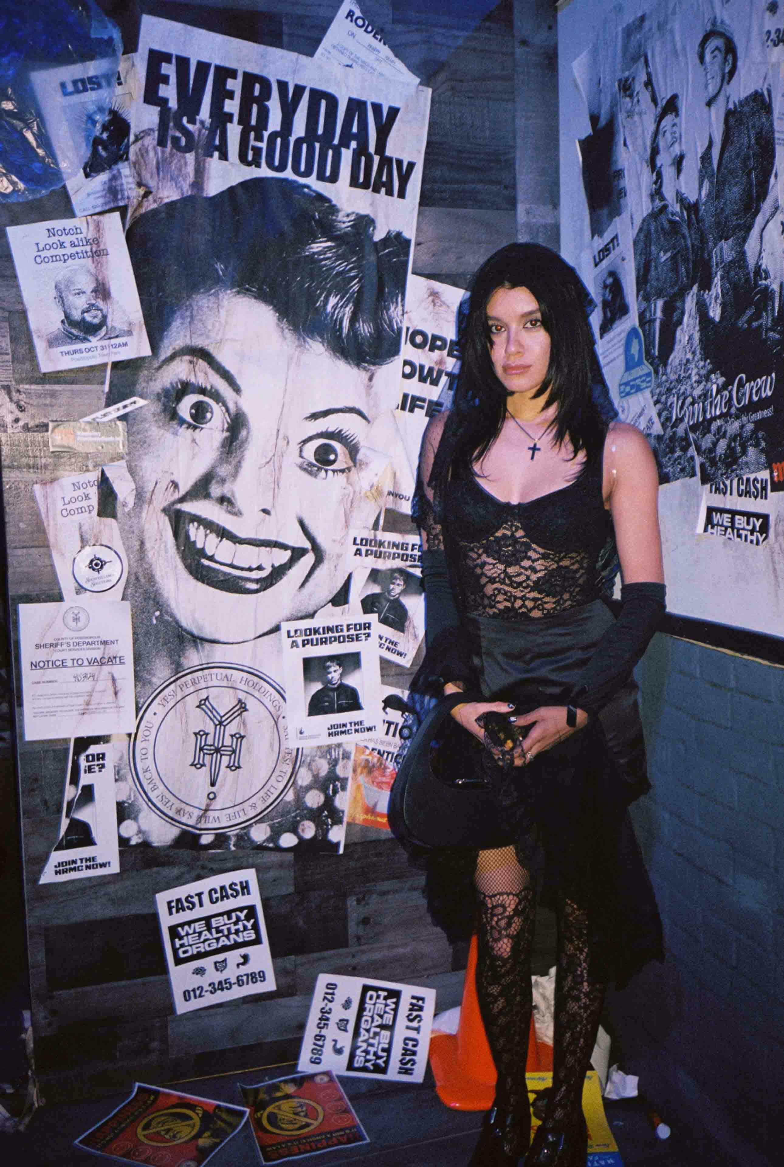 A woman standing in front of a wall covered in posters.