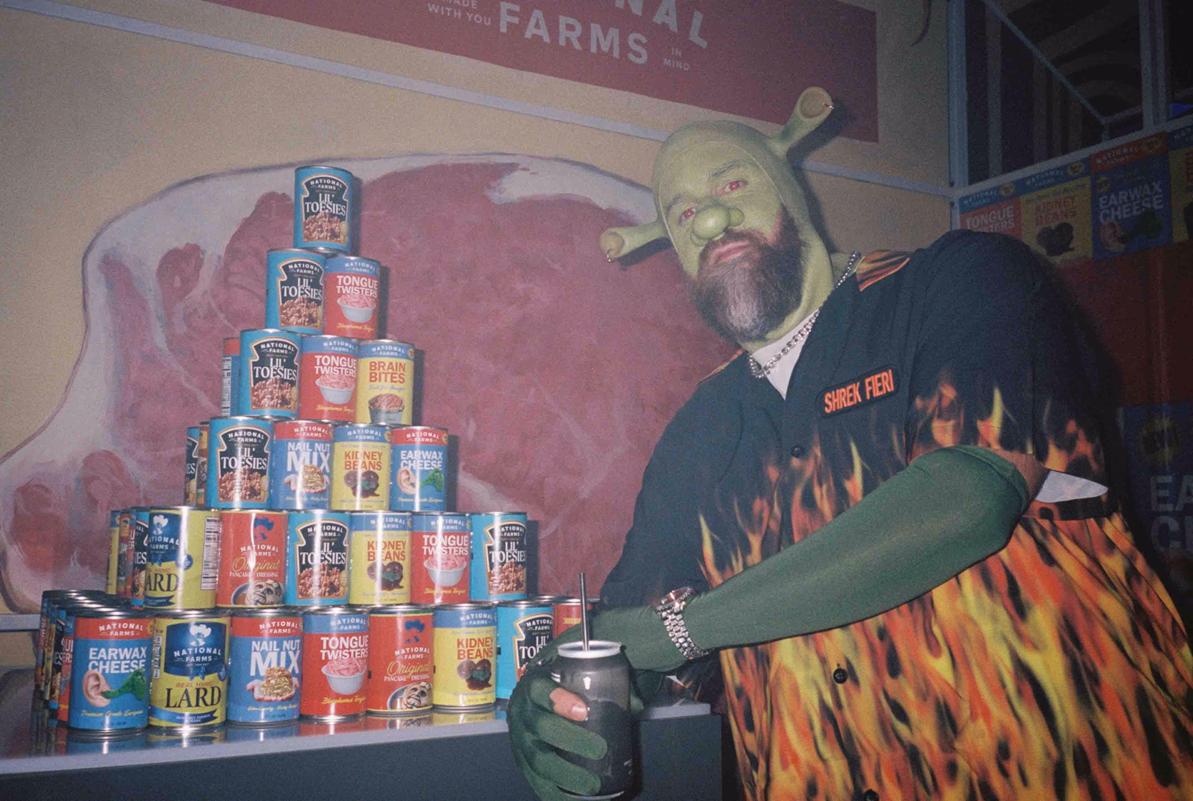 a man dressed as shrek standing next to a tower of canned goods